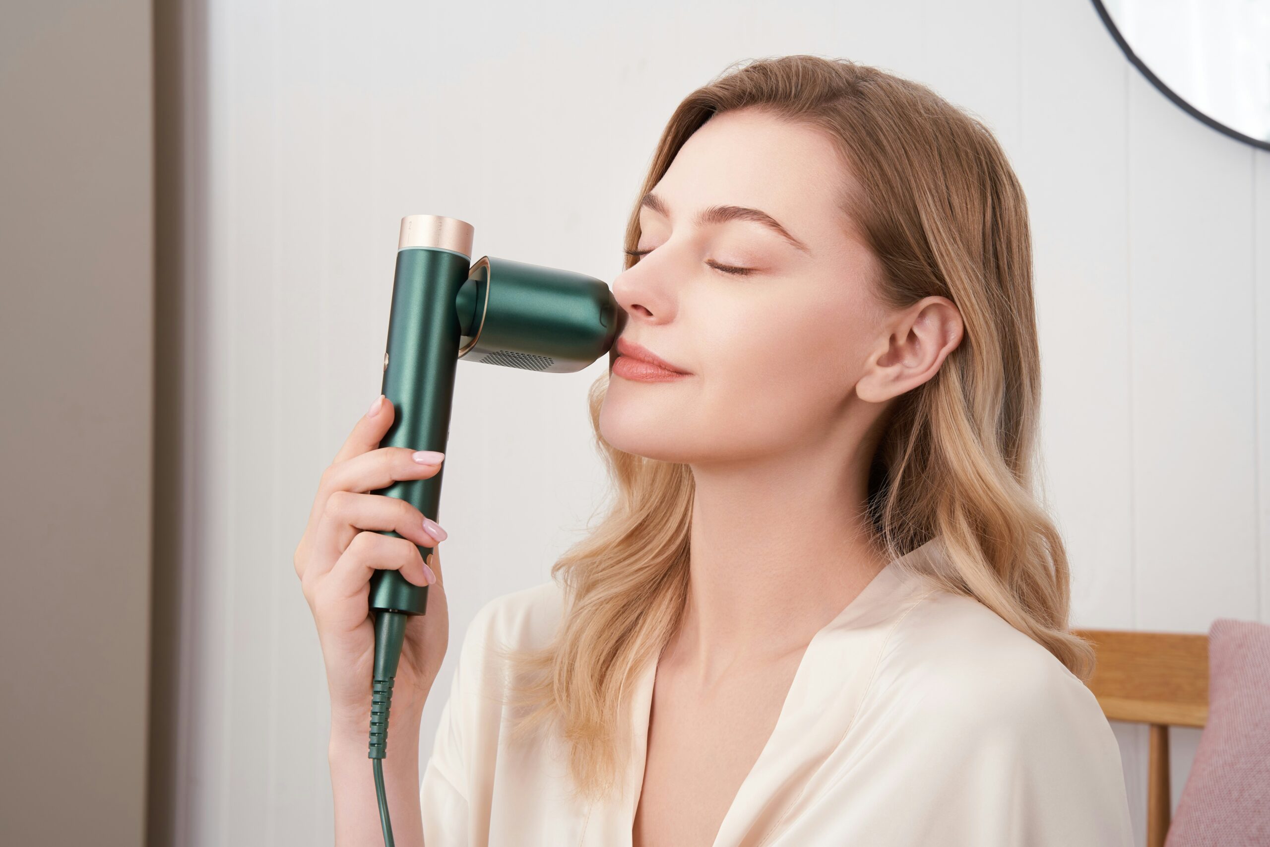 Woman using a green facial steamer beauty tech device at home